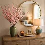 A green vase of pink cherry blossom branches sits on a console table - thumbnail number 9