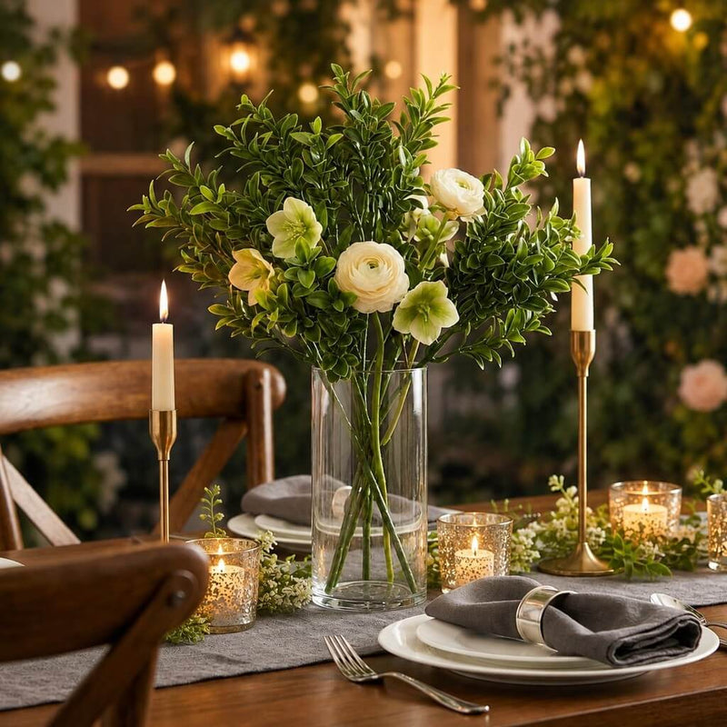 Green boxwood sprays with white flowers in a glass vase on a table - thumbnail number 2