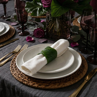 Banana leaf napkin ring holding a white napkin on layered plates - thumbnail number 6