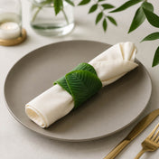 Banana leaf napkin ring holding a folded white napkin on a grey plate - thumbnail number 9