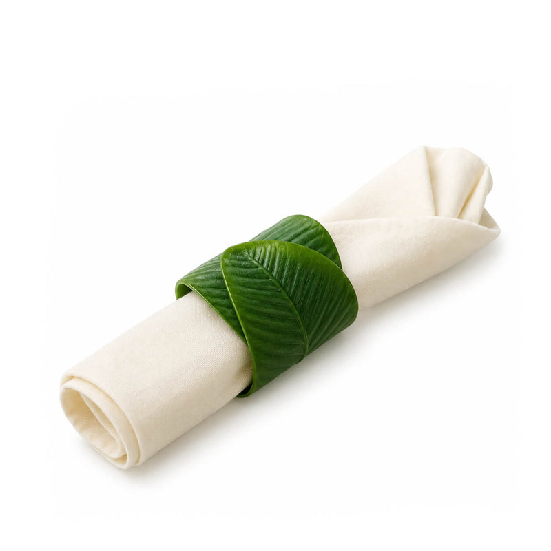 Banana leaf napkin ring holding a folded white napkin isolated on white - thumbnail number 2
