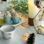 Decorative dessert setup with cupcakes, candles, and fairy lights on a table. - thumbnail number 1