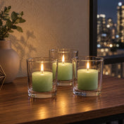 Three lit green votive candles in clear glass holders on a wooden tabletop at night - thumbnail number 9
