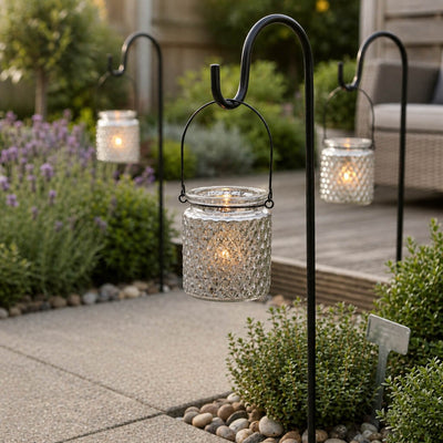 Three lit patterned glass lanterns on hooks along a garden path - thumbnail number 7