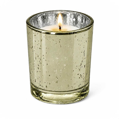 A single lit candle burning inside a Metallic Gold Mercury Votive Holder on a white surface - thumbnail number 3