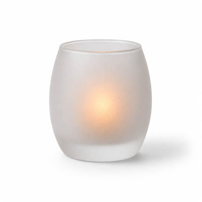 A glowing candle inside a frosted glass votive holder on a white background - thumbnail number 3