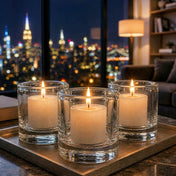 Lit votive candles in glass holders on tray with blurred city skyline backdrop - thumbnail number 9
