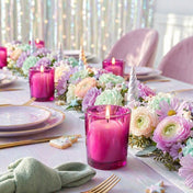 Lit white candles in pink holders on a pastel tablescape with unicorn horns and floral garland - thumbnail number 6