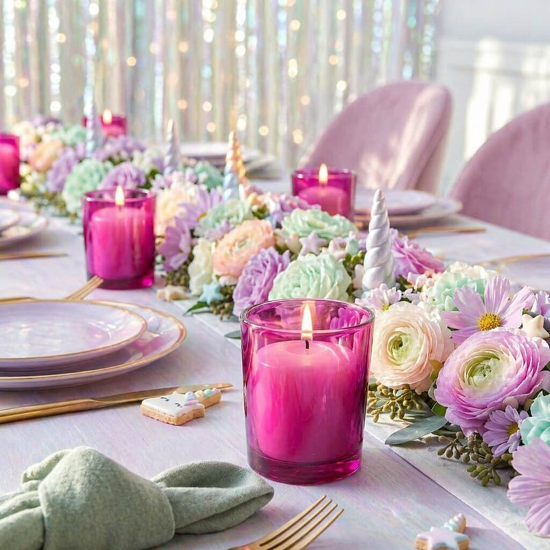 Lit white candles in pink holders on a pastel tablescape with unicorn horns and floral garland - thumbnail number 6