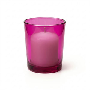 Unlit white candle in a pink glass holder on a solid white background