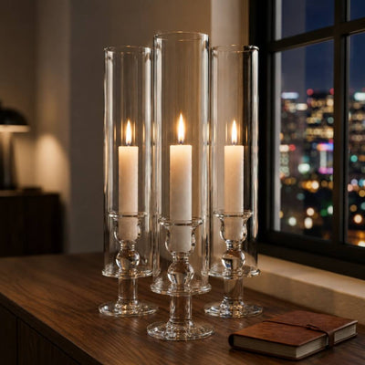 White vigil candles in tall glass holders beside window with city lights at night - thumbnail number 6