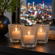 Three lit clear hobnail glass votive holders on a dark surface against a blurred city skyline at night - thumbnail number 8