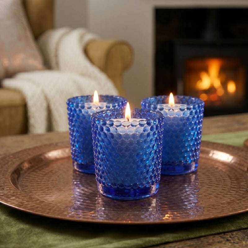 Blue hobnail votive holders with candles glowing on tray near cozy fireplace living room - thumbnail number 8