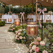 Rose gold hanging candle holders with pink floral decor along an outdoor wedding aisle - thumbnail number 3