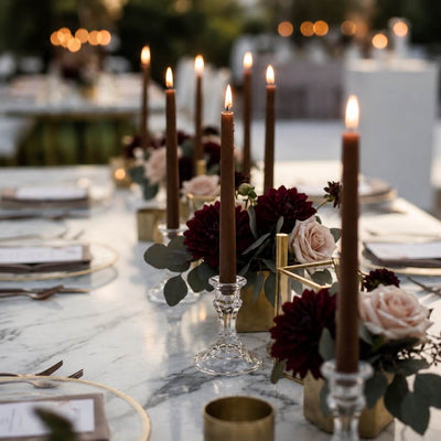 Outdoor dining table with lit brown taper candles and romantic floral arrangements - thumbnail number 5
