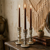 Three lit brown taper candles in silver holders on rustic wooden table - thumbnail number 7