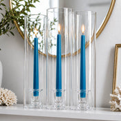 Blue taper candles in tall glass hurricane holders on white shelf - thumbnail number 7