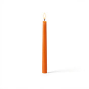 Single orange taper candle with flame on white backdrop - thumbnail number 2