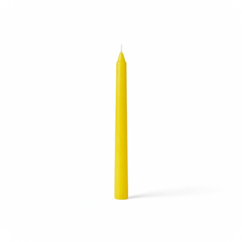 Single yellow taper candle on white backdrop - thumbnail number 1