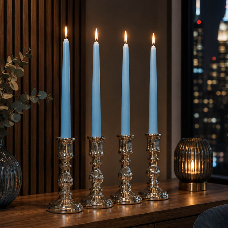 Light blue taper candles in silver holders on modern table by city window at night - thumbnail number 6