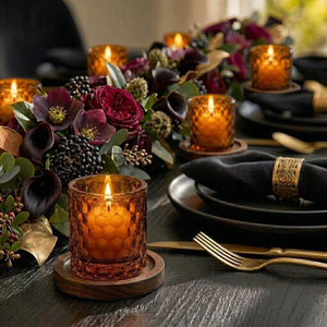 Decorative table setting with amber candles, black napkins, and floral arrangements.