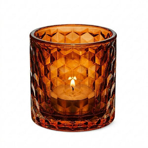 Amber honeycomb glass votive and tealight holder with lit tealight candle on white background