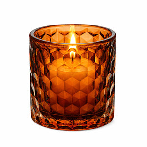 Amber honeycomb glass votive and tealight holder with lit candle on white background