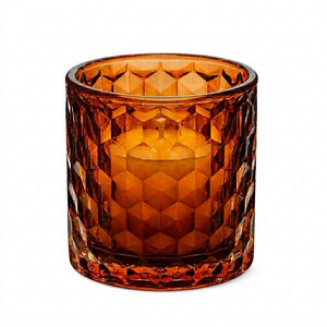 Amber honeycomb glass votive and tealight holder with white candle on white background