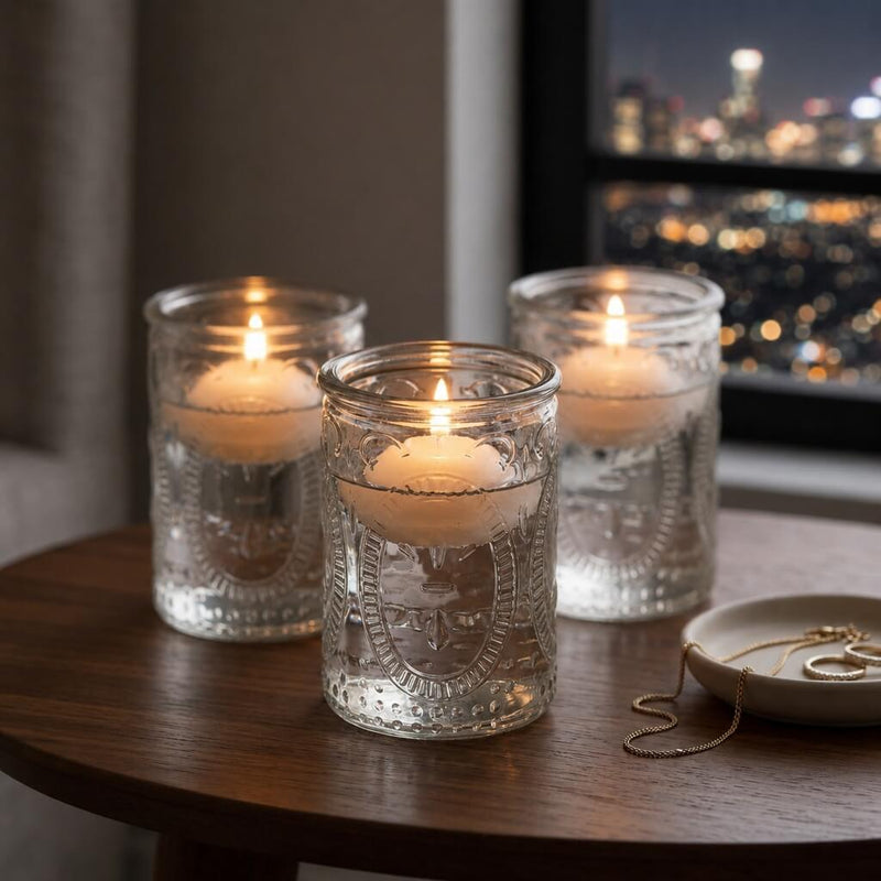 Three glass candle holders with glowing candles on wooden table by city window at night - thumbnail number 8