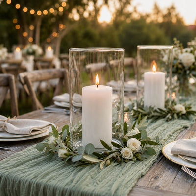 White pillar candle in a glass cylinder vase with a eucalyptus wreath on a green runner - thumbnail number 4