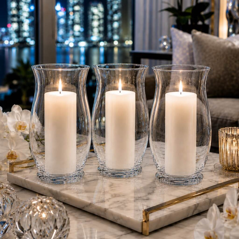 A lit white pillar candle burning inside a clear glass 10.5" Hurricane Vase on a dining tablescape - thumbnail number 8