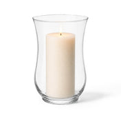 Warm candle flame glowing from within a classic clear glass 10.5 Hurricane Vase on white - thumbnail number 3