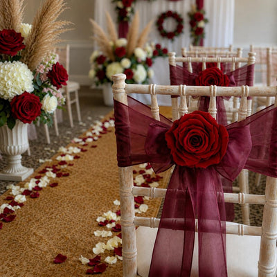 White chairs adorned with burgundy sashes and burgundy red preserved roses for a wedding aisle - thumbnail number 4