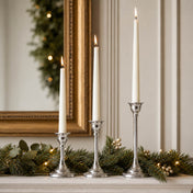 Three lit taper candles in silver holders on a mantle with evergreen garland - thumbnail number 8