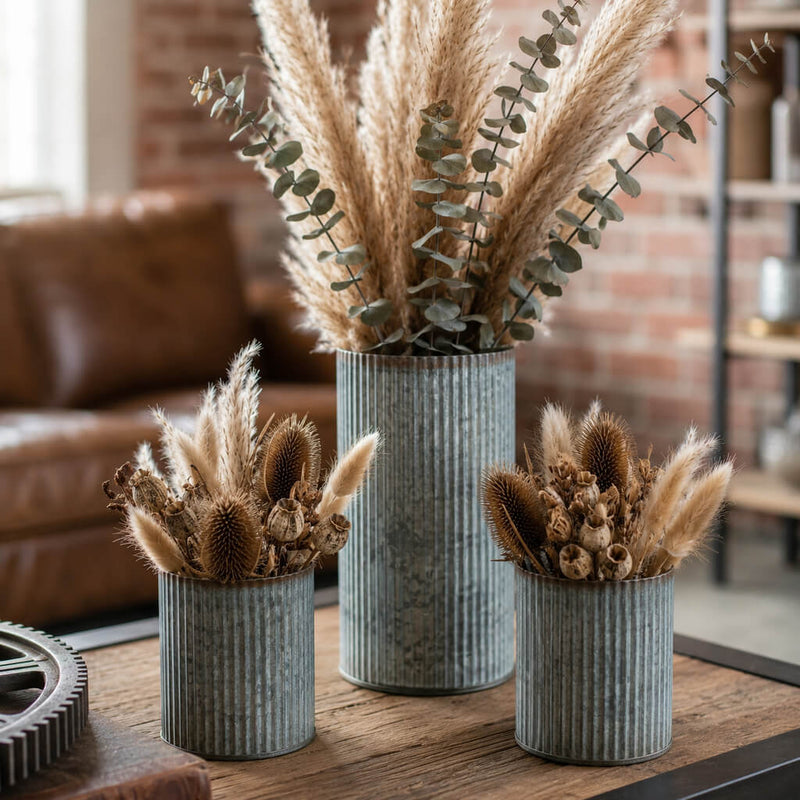 Dried pampas grass and botanical arrangements in three corrugated metal vases on a table - thumbnail number 6