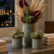 Succulents and dried foliage in corrugated metal vases on a table - thumbnail number 7