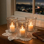 Three lit white pillars in a Hobnail Candle Holder trio on a doily with a nighttime city window view - thumbnail number 8