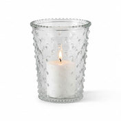 A lit white pillar candle inside a clear glass Hobnail Candle Holder on a white studio backdrop - thumbnail number 3