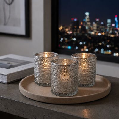 Set of pearly silver candle holders glowing on a tray with city lights background - thumbnail number 7