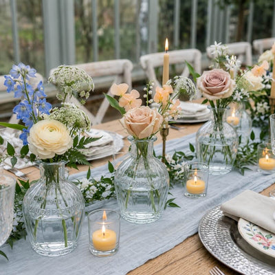 Flowers in vintage French parfum glass bottles on a table with candles - thumbnail number 5