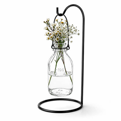 Vintage Bottle Hanging Glass Vase with small white flowers on a black metal stand - thumbnail number 3