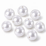 Several glossy white faux pearl craft beads with center holes arranged on a white surface - thumbnail number 1