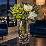 A tall glass vase with flowers sitting on a table, filled with navy blue and gold pearl beads - thumbnail number 9
