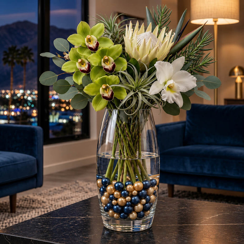A tall glass vase with flowers sitting on a table, filled with navy blue and gold pearl beads - thumbnail number 9