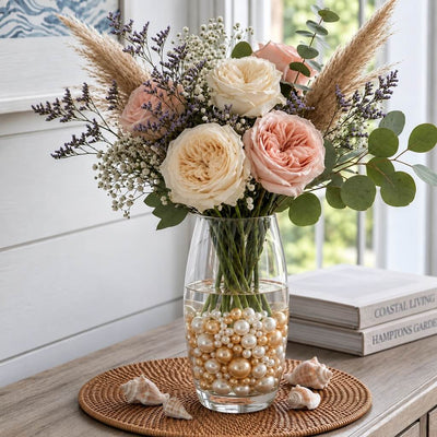 A glass vase with a floral arrangement sits on a woven mat, filled with off-white and gold pearl beads - thumbnail number 8