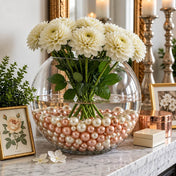 White dahlias in a glass bowl vase filled with rose gold and off-white pearl beads on a mantle - thumbnail number 10