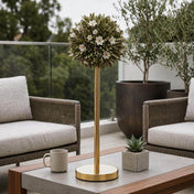 Gold metal stand topped with a green topiary sphere featuring small white flowers on an outdoor table - thumbnail number 9