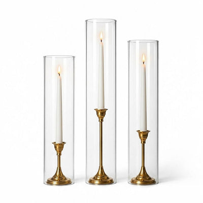 Lit white taper candles in gold holders with chimney glass candle shade cylinders - thumbnail number 2