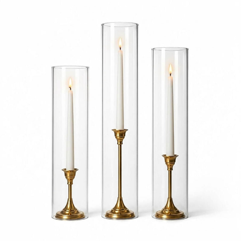 Lit white taper candles in gold holders with chimney glass candle shade cylinders - thumbnail number 2