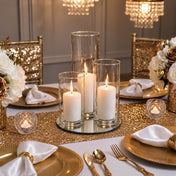 Lit pillar candles in glass cylinders on a gold-sequined table setting - thumbnail number 3